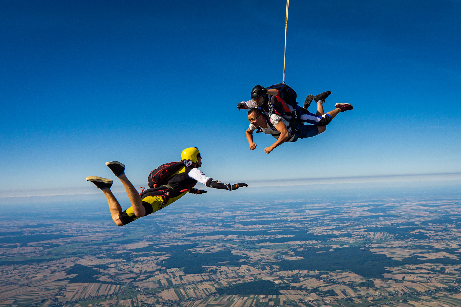 Tandem skydivers in freefall high above farmland
